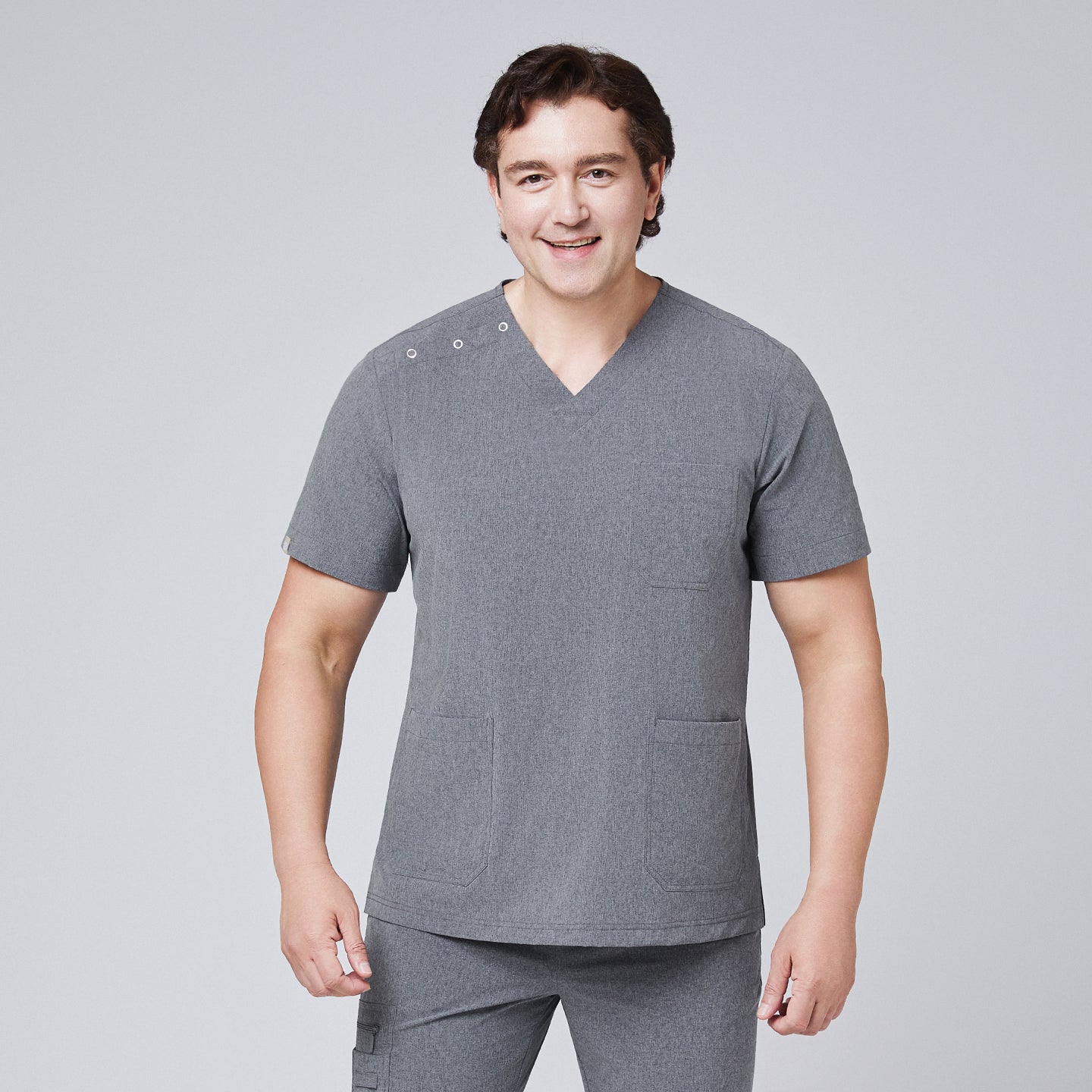 Image of Male model wearing ash gray scrub top with shoulder buttons and matching scrub pants, smiling confidently,Ash Gray